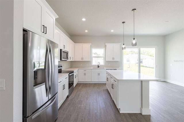 kitchen featuring a center island, white cabinets, sink, appliances with stainless steel finishes, and dark hardwood / wood-style flooring