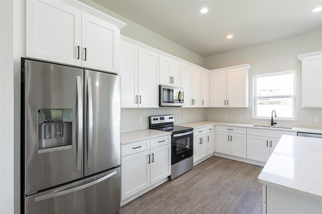 kitchen featuring light wood-type flooring, stainless steel appliances, white cabinetry, and sink