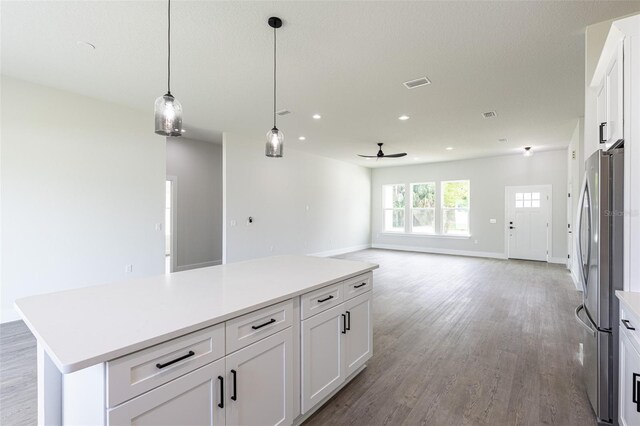 kitchen with white cabinets, ceiling fan, stainless steel fridge, and a kitchen island