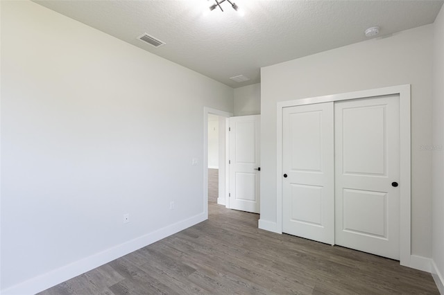 unfurnished bedroom featuring wood-type flooring, a textured ceiling, and a closet