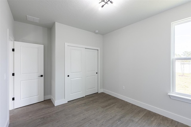 unfurnished bedroom featuring a closet, wood-type flooring, and a textured ceiling