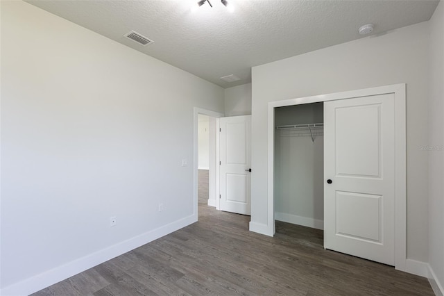 unfurnished bedroom with dark hardwood / wood-style floors, a textured ceiling, and a closet