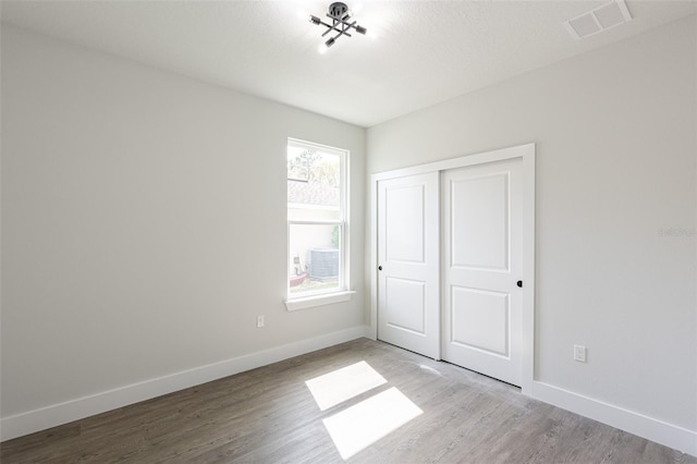 unfurnished bedroom with light wood-type flooring and a closet