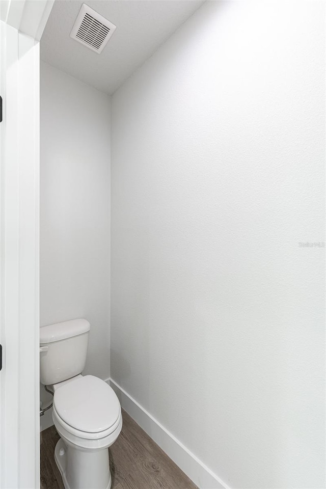 bathroom featuring toilet and wood-type flooring