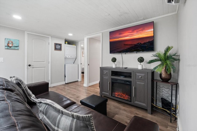 living room with light hardwood / wood-style flooring, stacked washer and clothes dryer, and crown molding