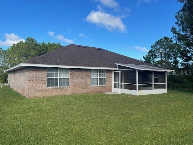 rear view of house with a yard and a sunroom