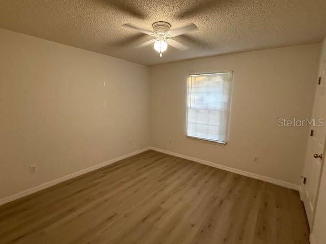 empty room featuring ceiling fan, a textured ceiling, and light hardwood / wood-style flooring