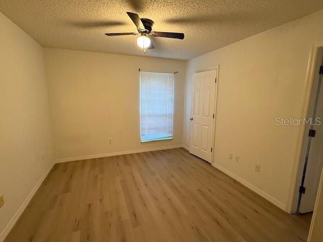 empty room featuring a textured ceiling, light wood-type flooring, and ceiling fan