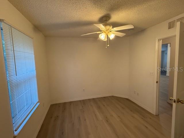 spare room with ceiling fan, wood-type flooring, and a textured ceiling