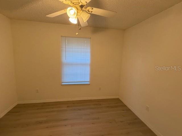 unfurnished room with ceiling fan, hardwood / wood-style floors, and a textured ceiling