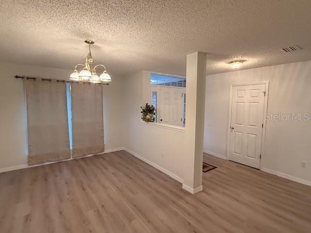 spare room with hardwood / wood-style flooring, a textured ceiling, and a chandelier