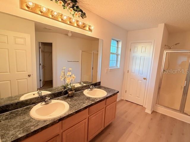 bathroom featuring walk in shower, vanity, a textured ceiling, and hardwood / wood-style flooring