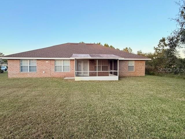 back of property featuring a sunroom and a lawn