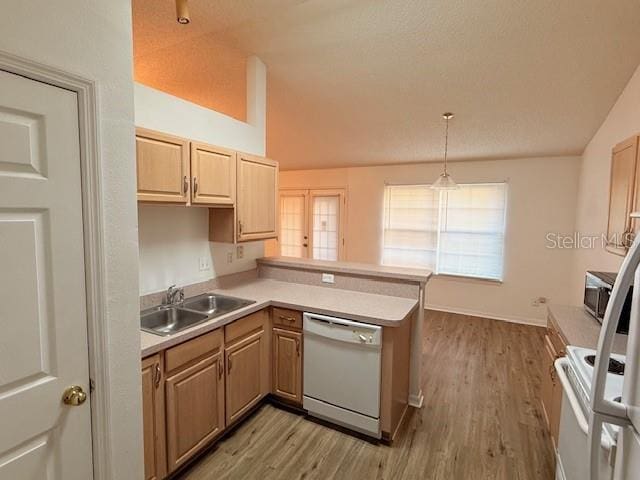 kitchen with decorative light fixtures, sink, white appliances, and kitchen peninsula