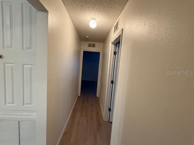 hallway with wood-type flooring and a textured ceiling