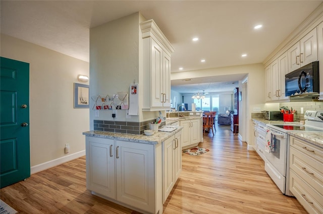 kitchen with kitchen peninsula, electric range, light hardwood / wood-style floors, and light stone counters