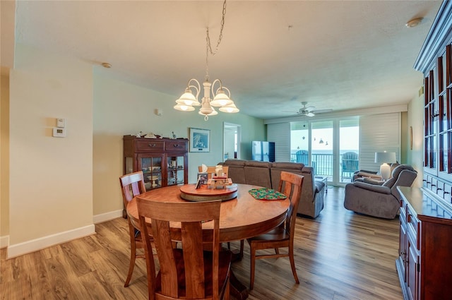 dining space with light hardwood / wood-style flooring and ceiling fan with notable chandelier