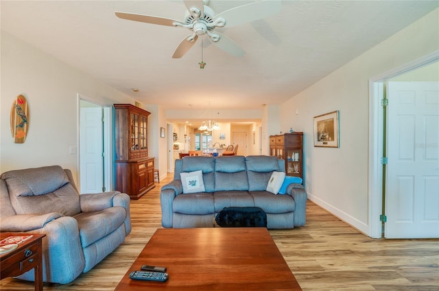 living room with ceiling fan with notable chandelier and light wood-type flooring