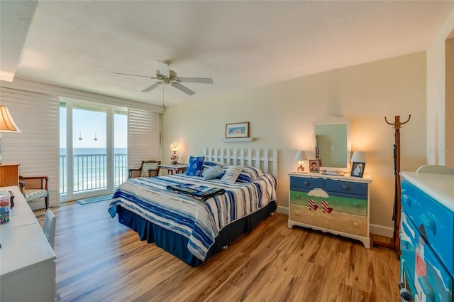 bedroom featuring ceiling fan, a water view, access to outside, and light hardwood / wood-style flooring