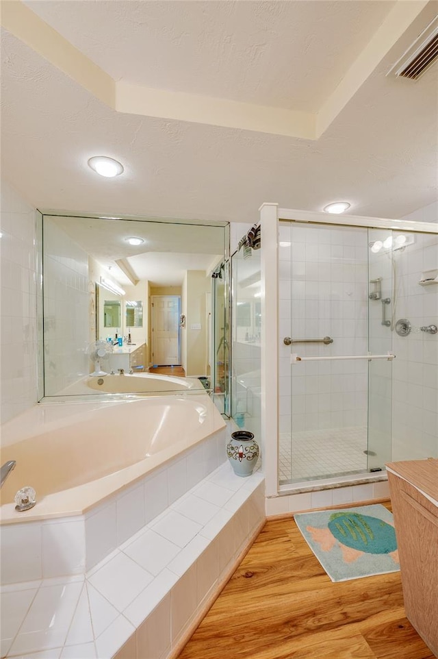 bathroom featuring plus walk in shower and wood-type flooring