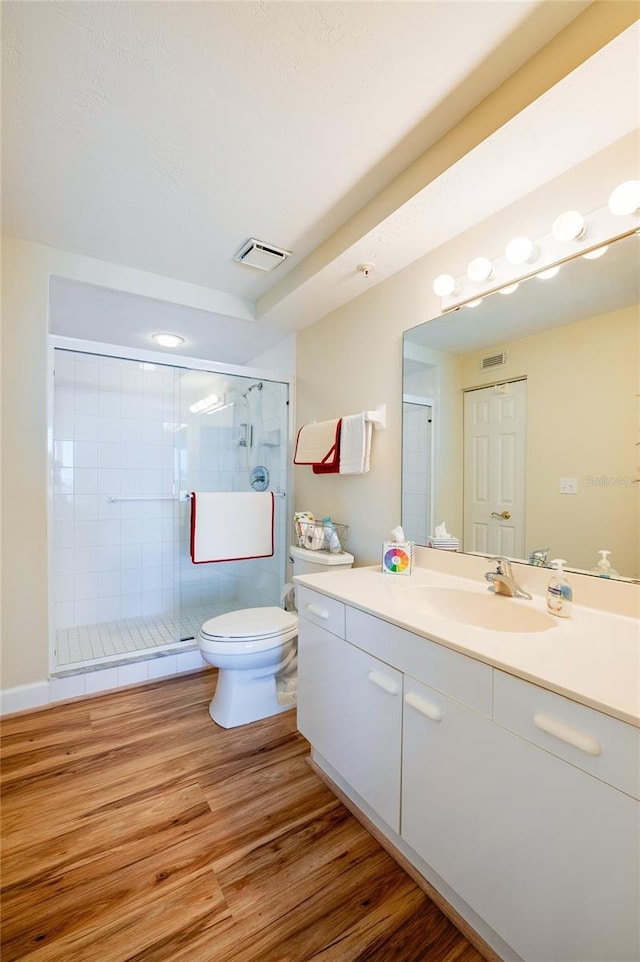 bathroom with hardwood / wood-style floors, vanity, toilet, and a shower with door