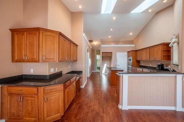 kitchen with a skylight, dark wood-type flooring, sink, high vaulted ceiling, and a kitchen island