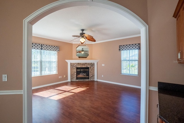 unfurnished living room featuring dark hardwood / wood-style floors, ceiling fan, ornamental molding, and a fireplace