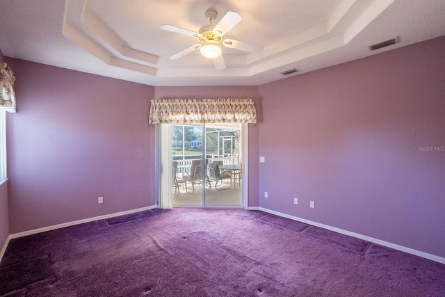 carpeted spare room featuring a raised ceiling and ceiling fan