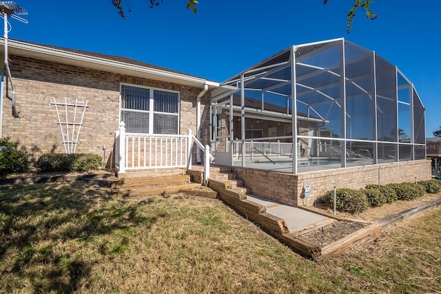 back of house featuring a yard, a pool, and glass enclosure