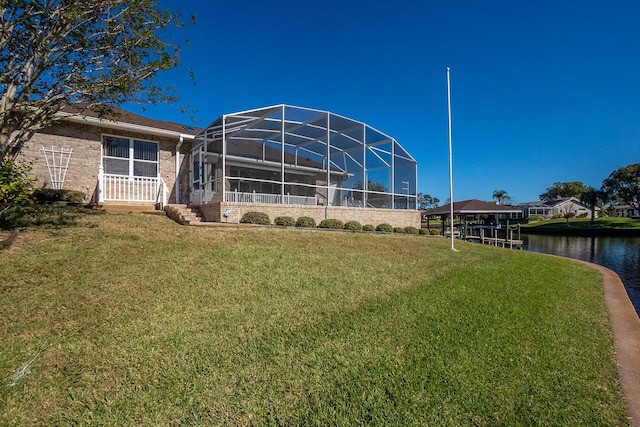 rear view of house featuring a lawn, glass enclosure, and a water view