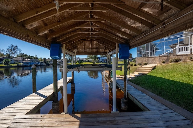 view of dock with a lawn and a water view