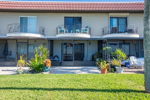 rear view of house featuring a lawn, a sunroom, and a balcony