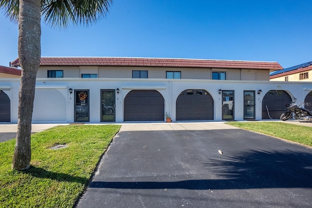 4 Ocean Palm Villa N, Flagler Beach, FL 32136 - townhome / multi-family property with a tiled roof, driveway, an attached garage, and a front yard