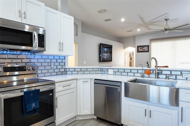 kitchen featuring white cabinetry, sink, kitchen peninsula, light hardwood / wood-style floors, and appliances with stainless steel finishes