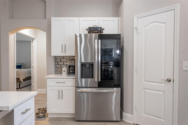 kitchen with stainless steel fridge with ice dispenser, tasteful backsplash, white cabinetry, and light hardwood / wood-style floors