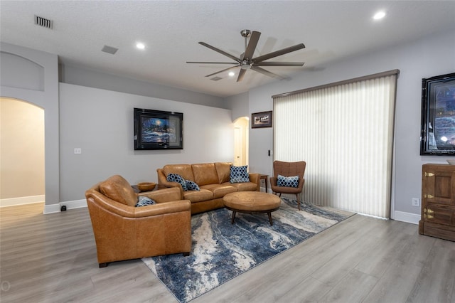 living room with ceiling fan, a textured ceiling, and light hardwood / wood-style flooring