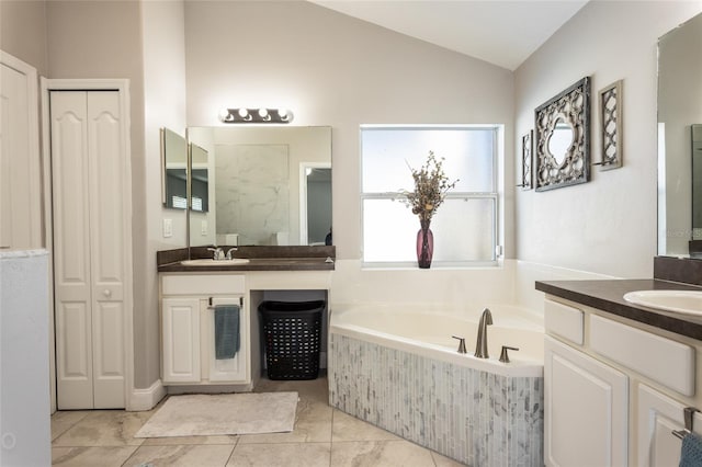 bathroom featuring vanity, a relaxing tiled tub, and vaulted ceiling