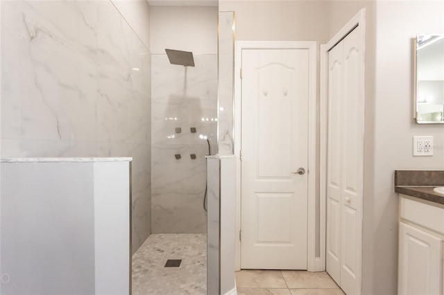 bathroom with tile patterned flooring, vanity, and a tile shower