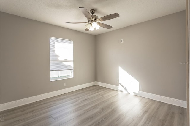 spare room featuring ceiling fan, light wood-type flooring, and a textured ceiling