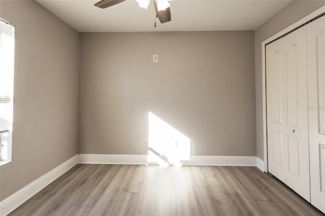 unfurnished bedroom with a closet, light hardwood / wood-style flooring, and ceiling fan