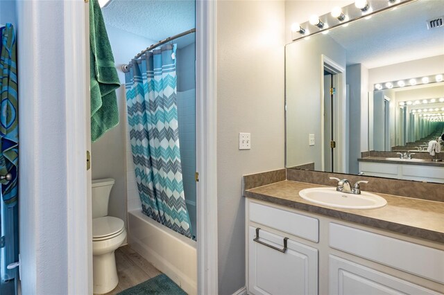 full bathroom featuring wood-type flooring, a textured ceiling, toilet, shower / bath combo with shower curtain, and vanity