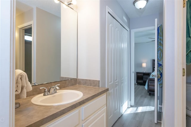 bathroom with hardwood / wood-style floors, vanity, ceiling fan, and a textured ceiling