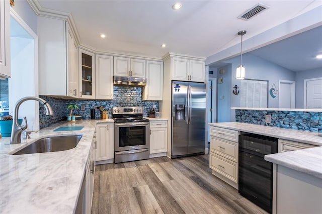 kitchen featuring sink, hanging light fixtures, stainless steel appliances, wine cooler, and lofted ceiling