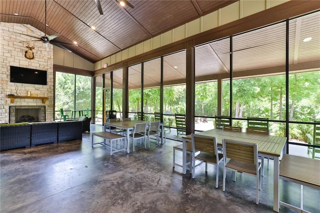 unfurnished sunroom with ceiling fan, wood ceiling, a fireplace, and vaulted ceiling