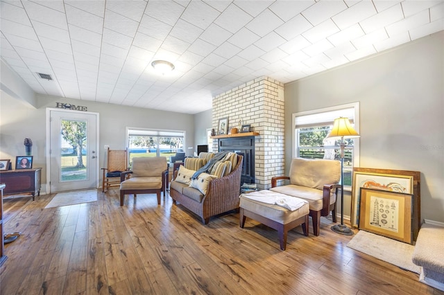 living room featuring hardwood / wood-style flooring, a brick fireplace, and plenty of natural light