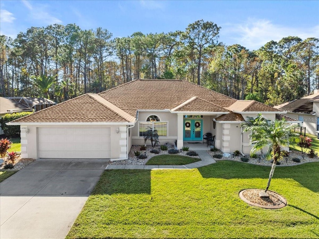 view of front facade featuring french doors, a garage, and a front lawn