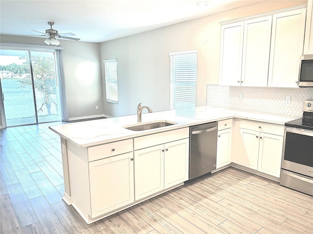 kitchen with kitchen peninsula, sink, appliances with stainless steel finishes, and light hardwood / wood-style flooring