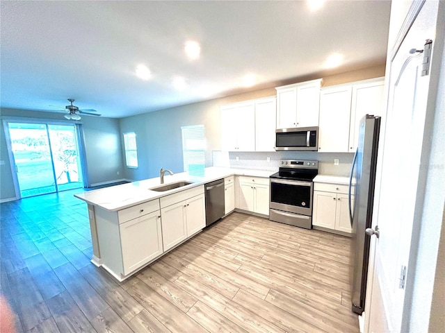 kitchen featuring kitchen peninsula, stainless steel appliances, light hardwood / wood-style flooring, and sink