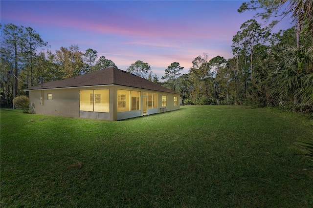 back house at dusk featuring a yard