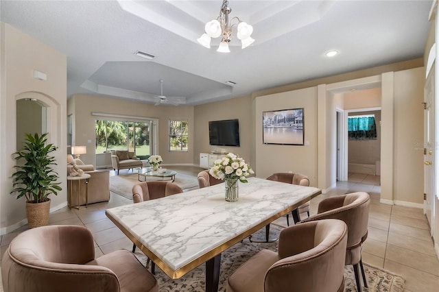 dining room featuring a tray ceiling, light tile patterned floors, and ceiling fan with notable chandelier